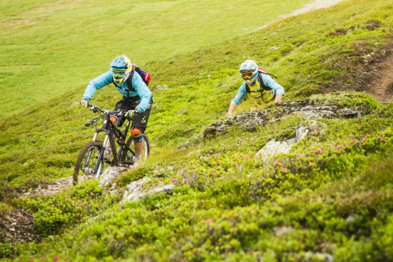 Young male and female mountain bikers cycling on hillside track